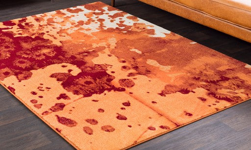 An orange Surya low pile rug on a wooden floor.