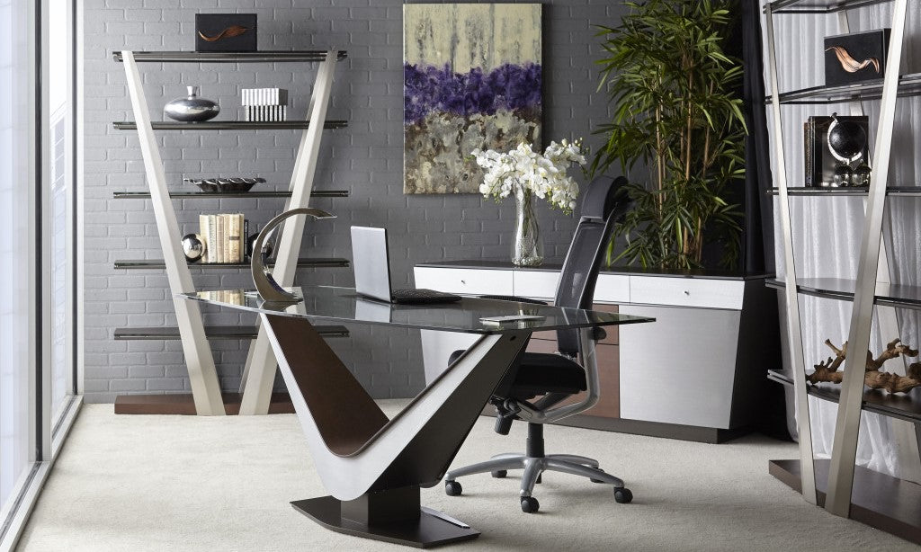 A modern home office with sleek furniture including a BDI glass Victor Desk and bookshelves.
