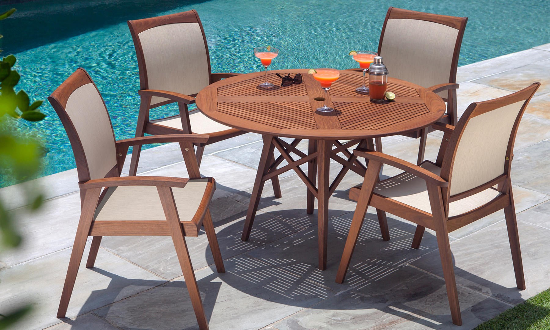 A Jensen Leisure Opal Round Table with Topaz Chairs near a pool.